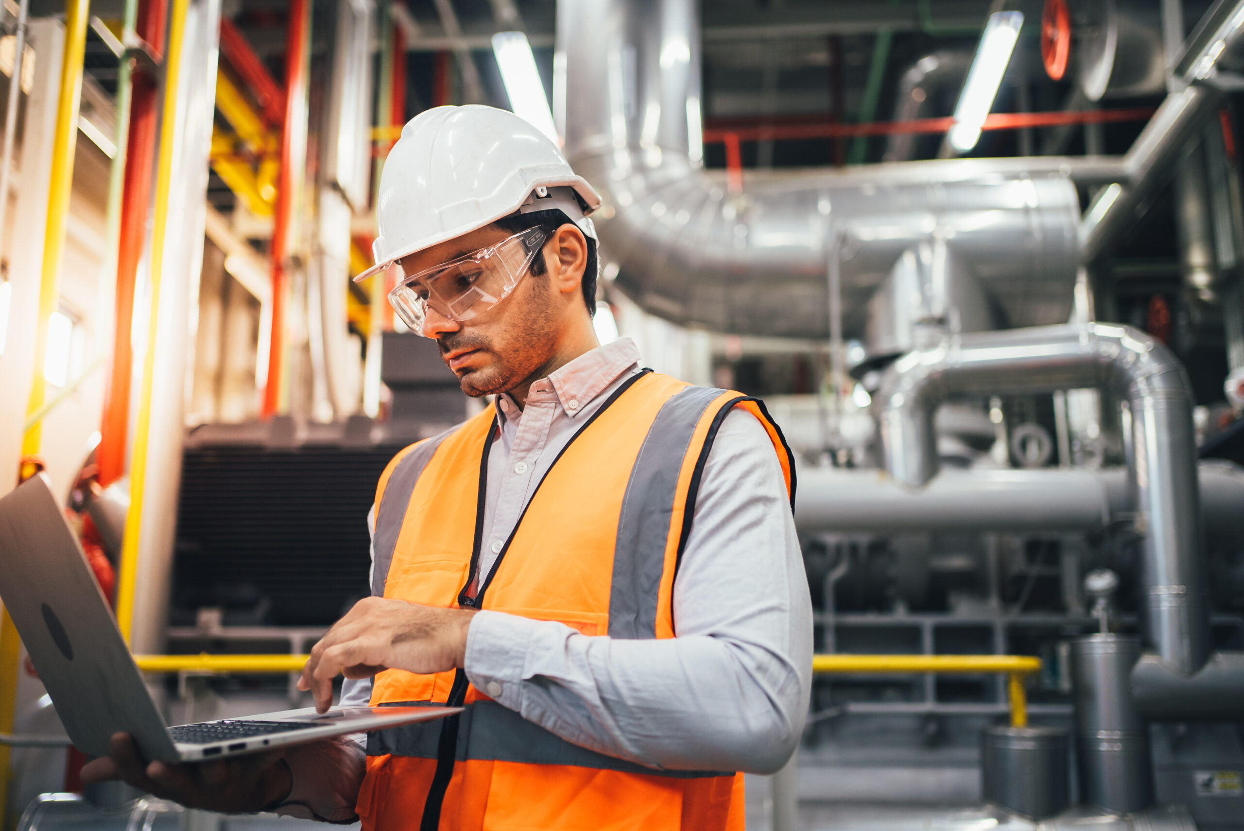 Professional worker of modern factory using laptop controlling program to automatic machinery. Engineering with laptop Programmable Logic Controller to manage large machine working full automatic.